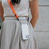 Woman in brown dress with Catalyst dropproof case over shoulder with orange neck lanyard