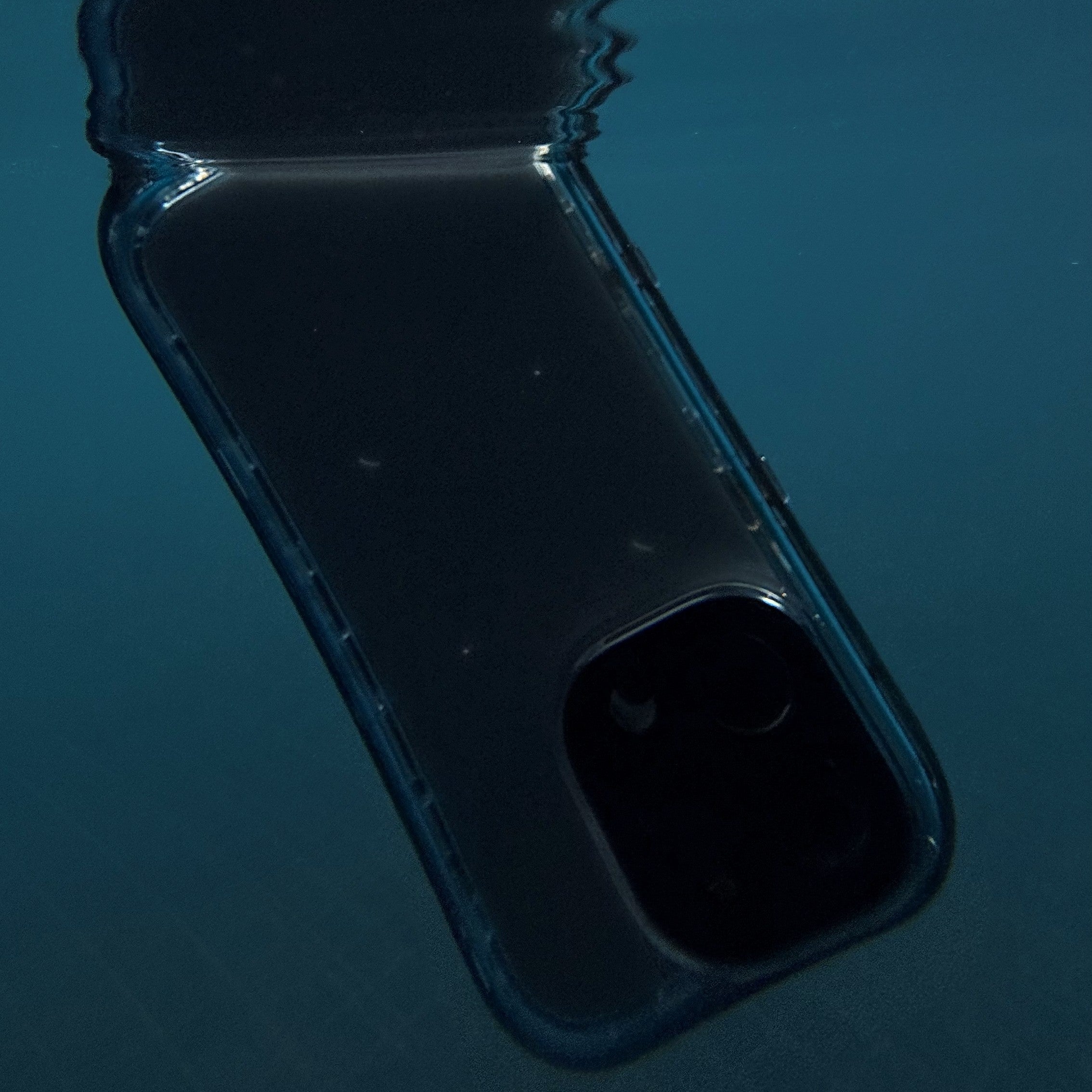 An iPhone 16 Pro Max, shielded in Catalyst's black waterproof case, is submerged underwater against a serene blue backdrop.