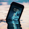 Catalyst waterproof case with an image of a speedboat cutting through water on screen that is reflected onto the water at sunset