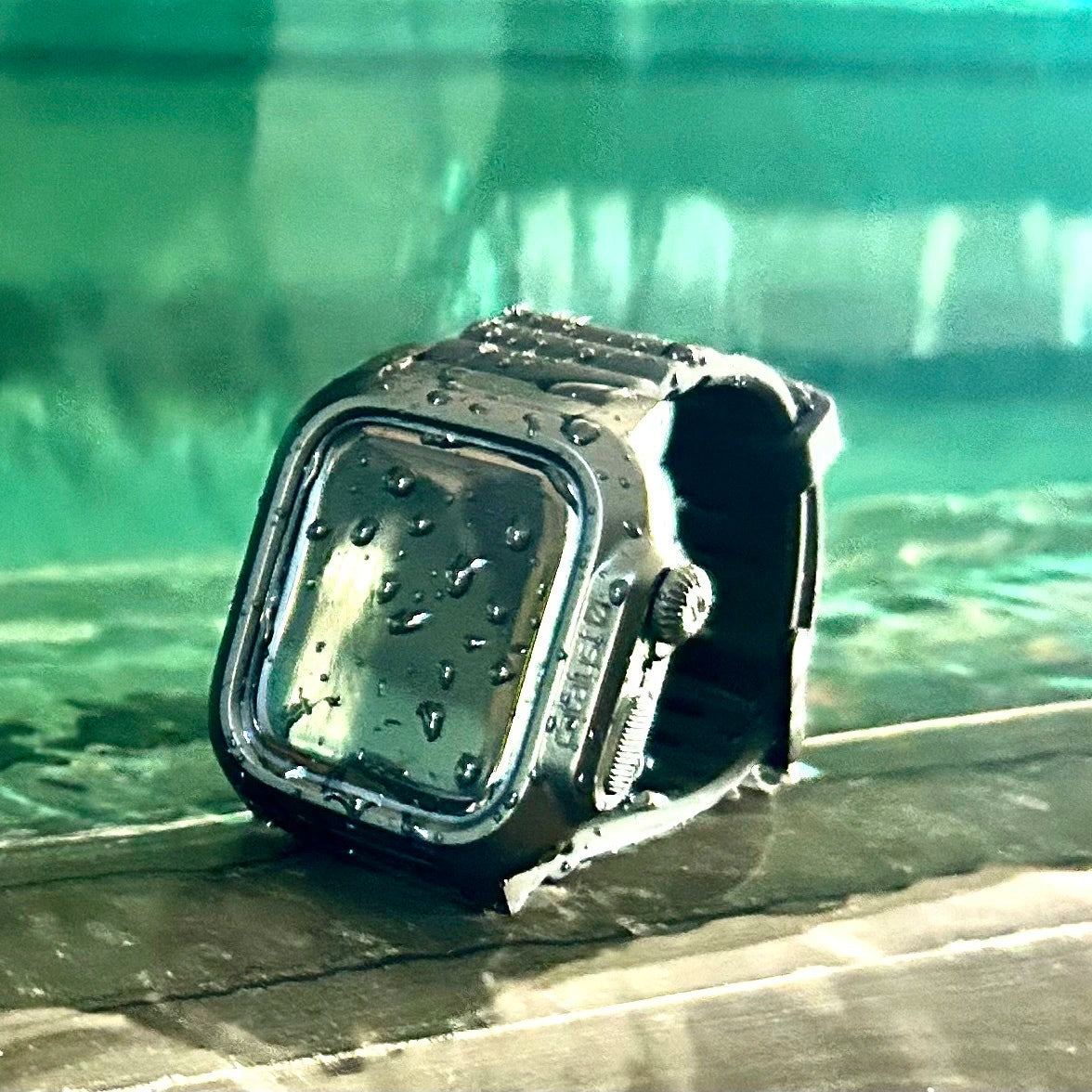 The Catalyst Waterproof Case for Apple Watch sits on a damp ledge with droplets glistening on its surface, effortlessly sealing out water against a blurred green background.