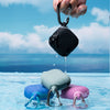 Near the pool, four vibrant waterproof devices in blue, green & pink AirPods 4 waterproof cases with a smooth one-piece design and handy carabiners are displayed. A hand holds a Catalyst AirPods (Gen 4) in a black waterproof case, its silicone exterior gleaming with water droplets to highlight its durability and style.